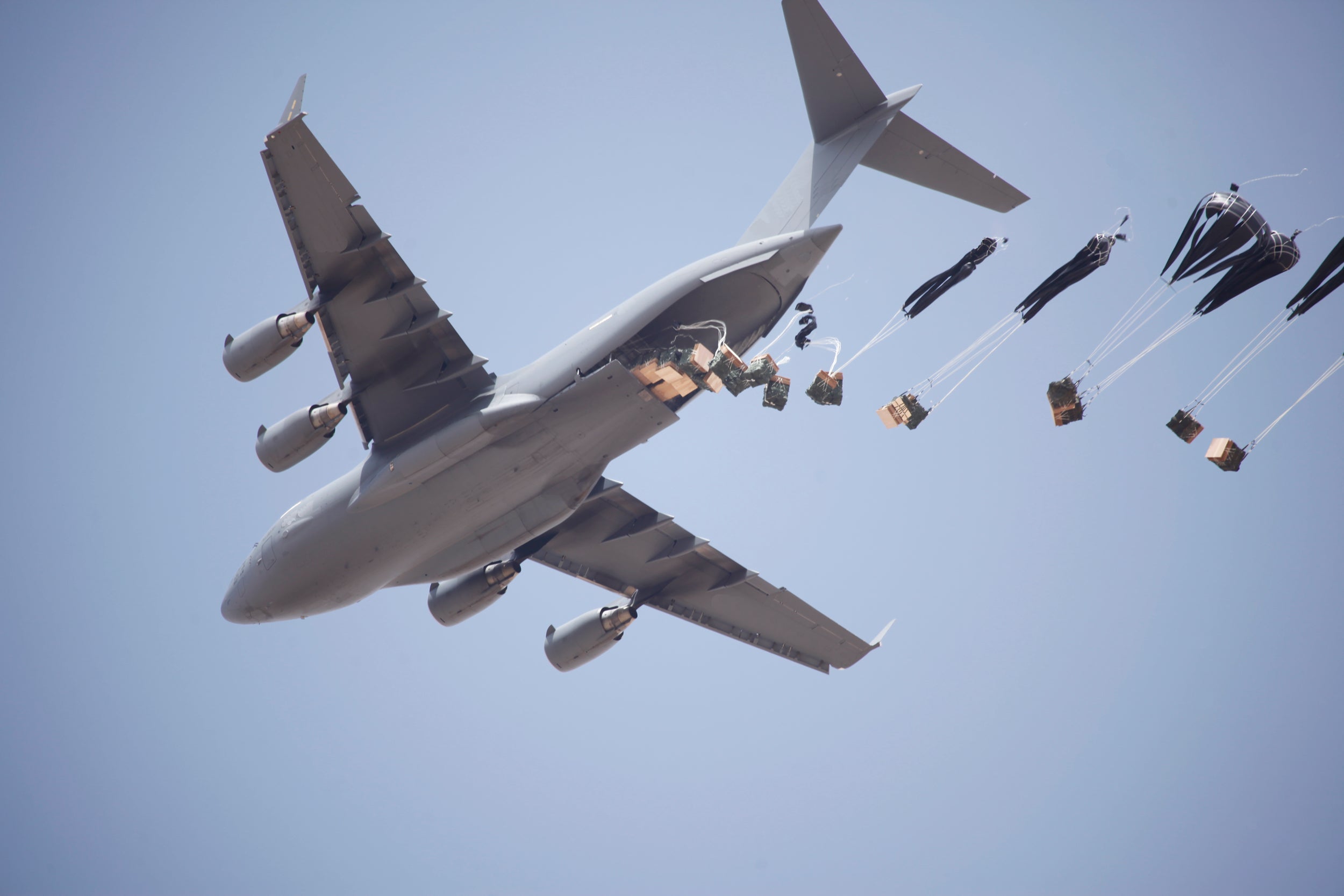 Airdrop of high velocity cargo parachutes deploying from a large c130 airplane.