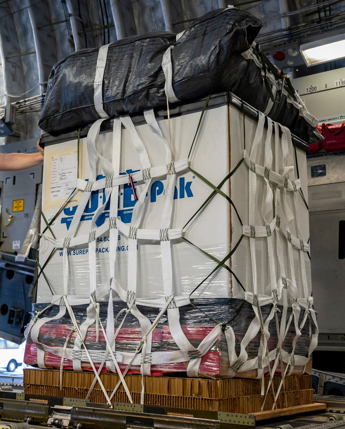Low Cost Container (LCC) rigged around a CDS load with a Low Velocity (LCLV) cargo parachute on top, inside a cargo aircraft ready for airdrop.